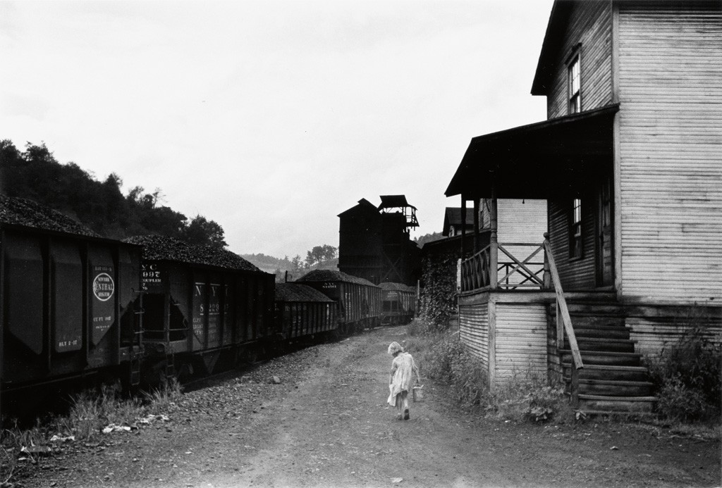 Image via Swann Galleries. “Coal Miner’s Child Carrying Home Can of Kerosene, Company houses, Scotts Run, W. Va.,” 1938; printed 1977. Marion Post Wolcott. 