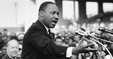 Martin Luther King, Jr. giving a speech at a podium, black and white photo
